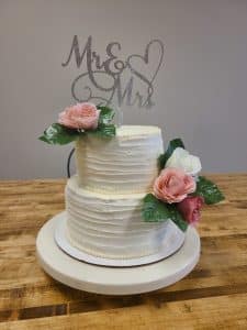 two tier white wedding cake with silk flowers